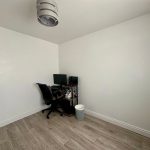 Minimalist home office with wooden floor and computer desk.