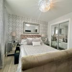 Elegant bedroom with mirror and patterned wallpaper.