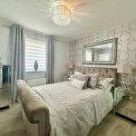 Elegant bedroom with floral wallpaper and mirrored furniture.