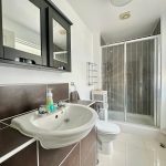 Modern bathroom with sink, shower, and cabinet.