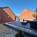 Modern garden patio with sofa and decorative wall.