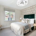 Modern bedroom with geometric wallpaper and chandelier.