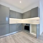 Modern kitchen with grey cabinets and wood flooring.