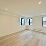 Empty room with wooden floor and large windows.