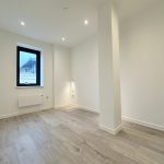 Empty room with wooden flooring and window view.