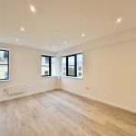 Empty room with wooden floor and large windows.
