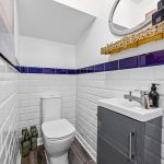 Modern bathroom with white tiles and purple accents.
