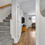 Modern hallway with staircase and living room view.