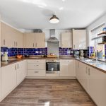 Modern kitchen with blue tiles and wooden floors.