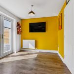 Modern room with yellow walls and wooden floor.