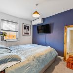 Cosy bedroom with blue accents and large mirror.