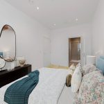 Modern bedroom with colourful bedding and wall art.
