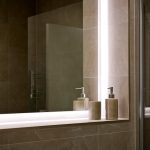 Modern bathroom with illuminated mirror and soap dispensers