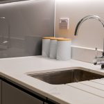 Modern kitchen sink with chrome faucet and canisters.