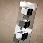 Modern chrome shower control panel on tiled wall