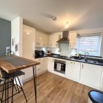 Modern kitchen with wooden table and appliances.