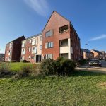 Modern red brick apartment building under clear blue sky.
