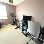 Home office with exercise bike and computer desk.