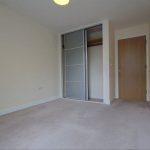 Empty room with beige carpet and sliding wardrobe.