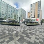 Urban courtyard surrounded by modern buildings and trees.