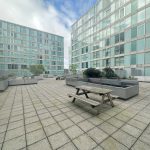 Modern apartment courtyard with benches and planters.