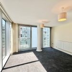 Sunny modern apartment with large windows and carpet.