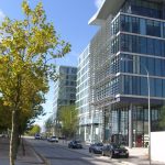 Modern office building with trees in urban setting.