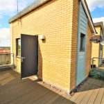 Sunny rooftop terrace with brick walls and open door.
