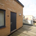 Modern rooftop terrace with wooden decking and glass railing.