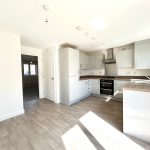 Modern kitchen with white cabinets and wood floor.