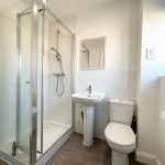 Modern bathroom with shower, sink, and toilet.
