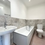 Modern bathroom with sink, bathtub, and toilet.