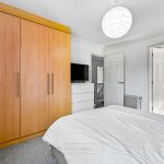 Modern bedroom with wooden wardrobe and white decor.