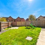 Sunny garden with grass, bench, and playset.