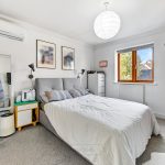 Modern bedroom with grey bed and decor.