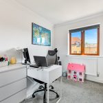 Home office with desk, map, window, and dollhouse.