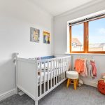 Bright baby room with crib and clothes.