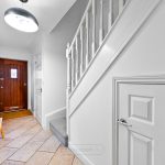Modern hallway with wooden front door and stairs.