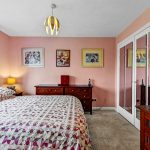 Comfortable bedroom with mirrored wardrobe and artwork.