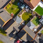 Aerial view of residential rooftops and colourful gardens.