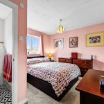 Cosy bedroom with bathroom, pink walls and furniture.