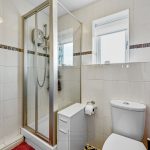 Modern bathroom with shower, toilet, and red towels.
