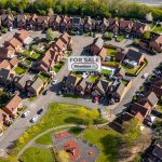 Aerial view of houses with 'For Sale' sign.