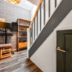 Modern home office under stairs with desk and monitors.