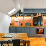 Modern kitchen with wooden table and grey cabinets.