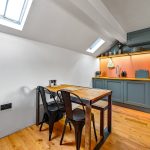 Modern kitchen with skylights and wooden dining table.