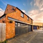 Charming brick building with wooden garage doors, sunset.