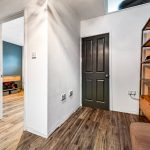 Hallway with wooden floor, dark doors, and shelves.