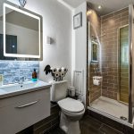 Modern bathroom with shower and illuminated mirror.