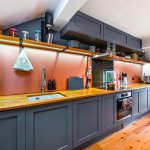 Modern kitchen with wooden countertops and grey cabinets.